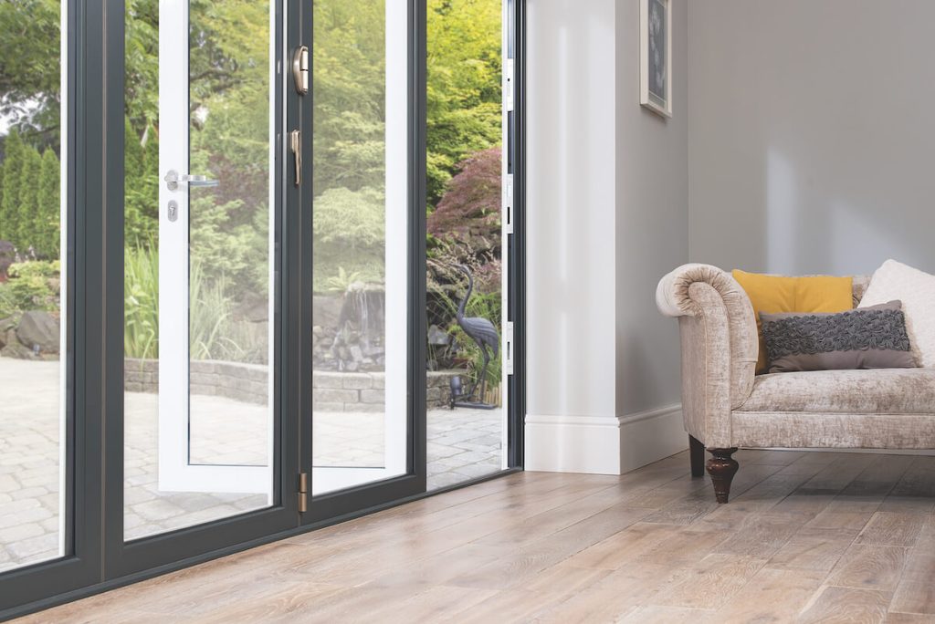 A living room featuring Origin aluminium bifold doors opening to a garden, highlighting the door’s design and natural light benefits for homes in {location}.