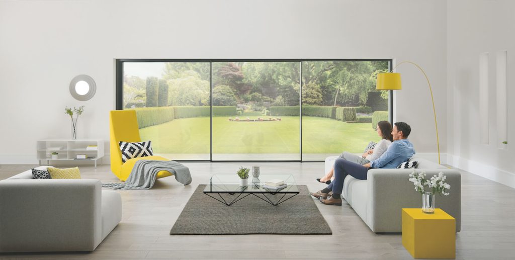 A living room with Origin aluminium sliding doors, providing a clear view of the garden, highlighting the sleek design and natural light for homes in {location}.